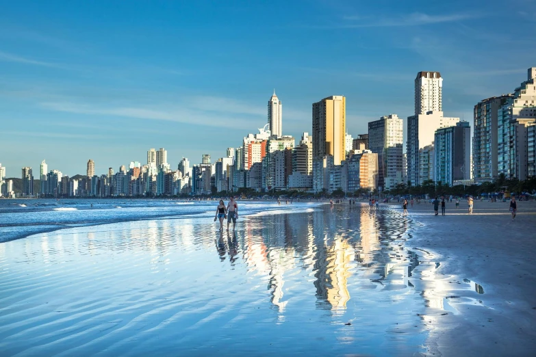 a group of people walking along a beach next to the ocean, by Felipe Seade, pexels contest winner, art nouveau, super wide view of a cityscape, brazilian, high quality reflections, where a large