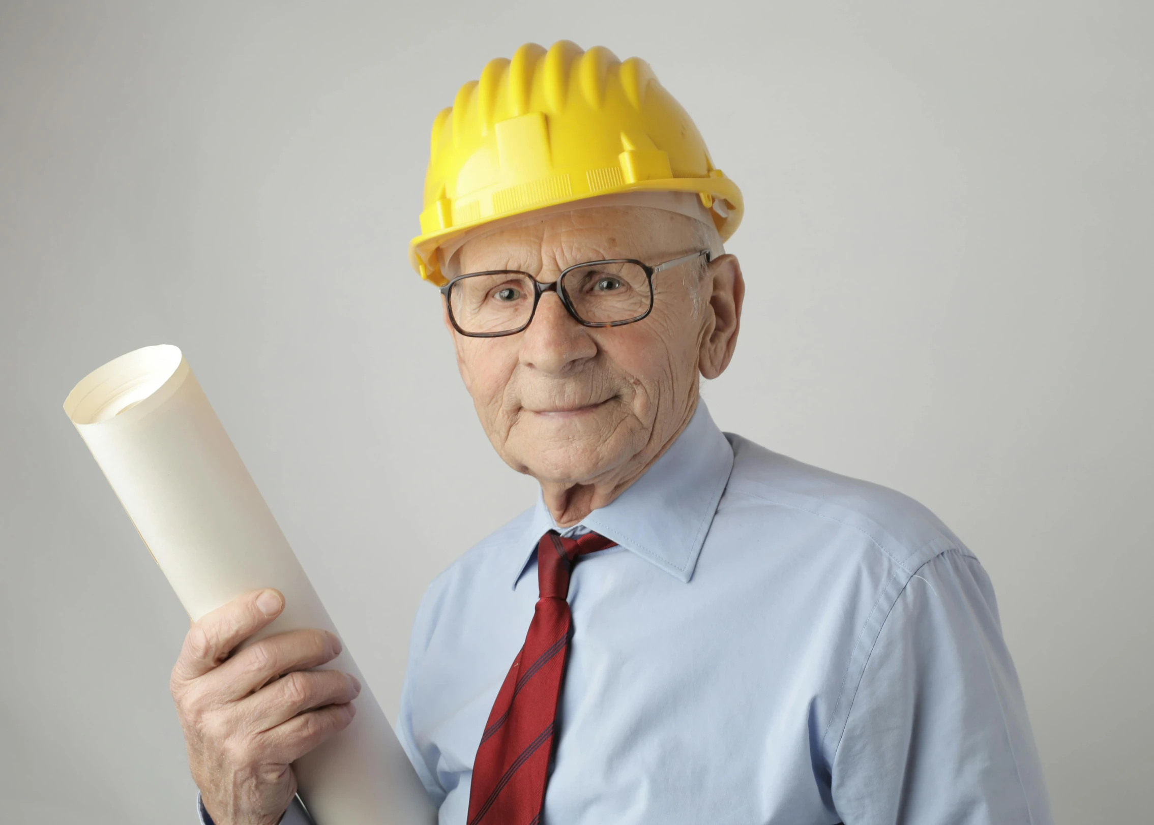 a man in a hard hat holding a roll of paper, a colorized photo, inspired by Murray Tinkelman, pexels contest winner, wearing medium - sized glasses, tall thin build, wise old man, professional cosplay