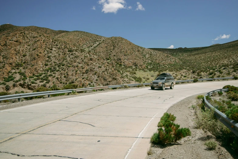 a car that is sitting on the side of a road, les nabis, wind river valley, paved roads, 90s photo