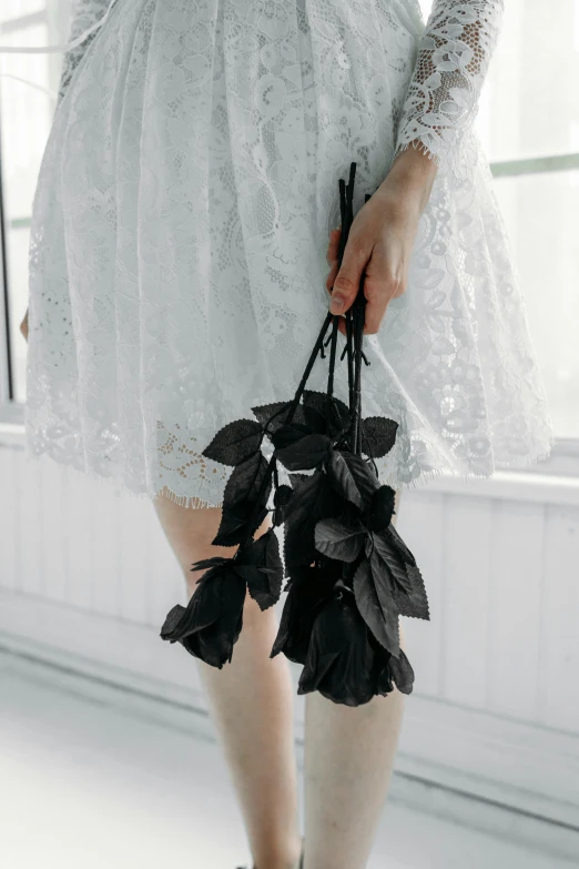 a woman in a white dress holding a bunch of black roses, inspired by Elsa Bleda, unsplash, garters, ulzzang, all black matte product, dressed in a worn