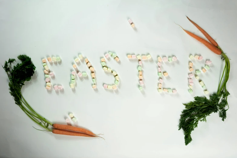 a couple of carrots sitting on top of a table, an album cover, inspired by Cerith Wyn Evans, unsplash, marshmallows, easter, detailed letters, molecular gastronomy