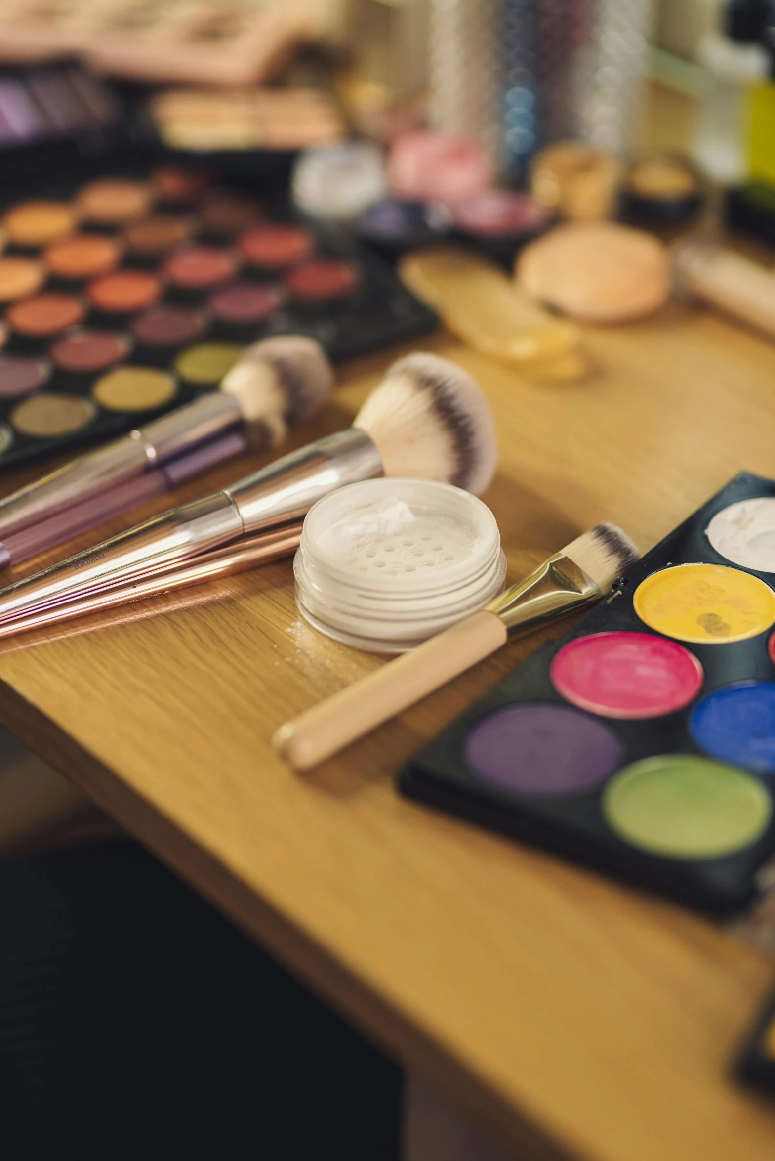 a wooden table topped with lots of makeup brushes, figuration libre, facepaint, multi - coloured, skincare, deep colour\'s