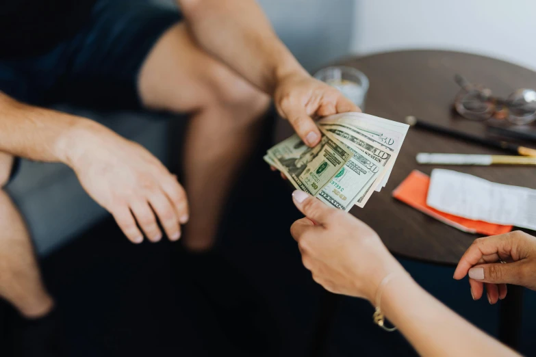 a person handing a stack of money to another person, by Daniel Lieske, pexels contest winner, sitting on a mocha-colored table, 🤬 🤮 💕 🎀, thumbnail, fan favorite