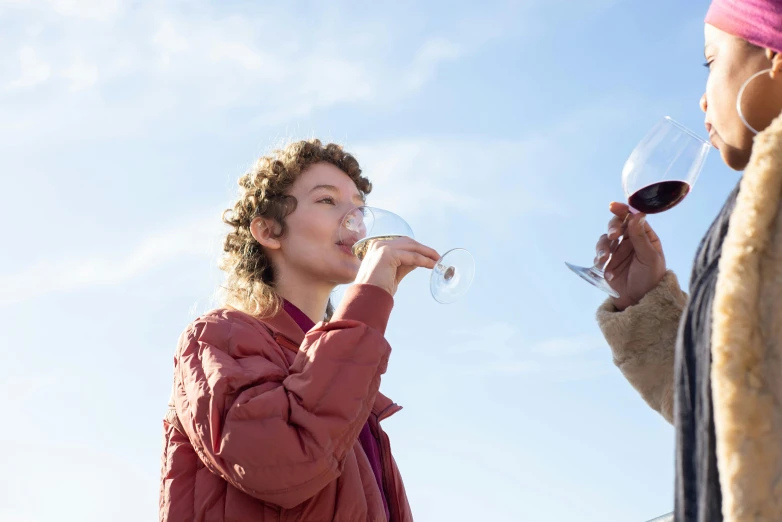 a woman standing next to a man holding a glass of wine, by Julian Hatton, pexels contest winner, blue sky, eleanor tomlinson, bottom angle, tastes