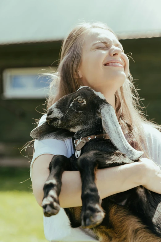 a woman holding a baby goat in her arms, pexels contest winner, pokimane, black, a still of a happy, beautifully daylight