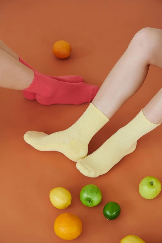 a woman sitting on top of a table next to a pile of fruit, socks, yellow hue, thumbnail, coral red