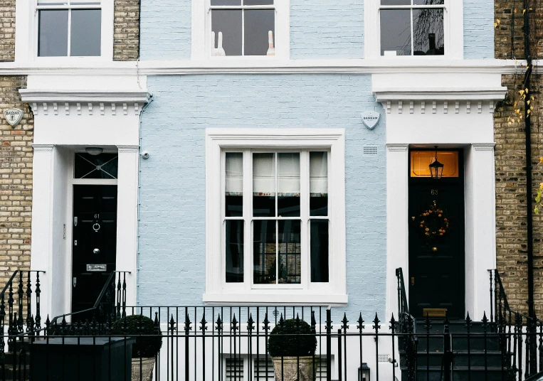 a red fire hydrant sitting in front of a blue building, inspired by Edward Kemble, neoclassicism, bay window, pastel blue, black house, terraced