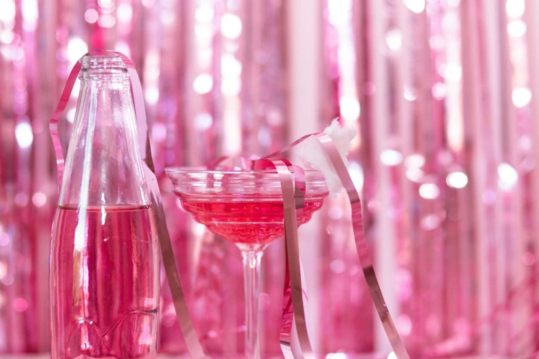 a glass filled with pink liquid next to a bottle, by Julia Pishtar, pexels, ribbons, disco party, movie scene close up, brightly lit pink room