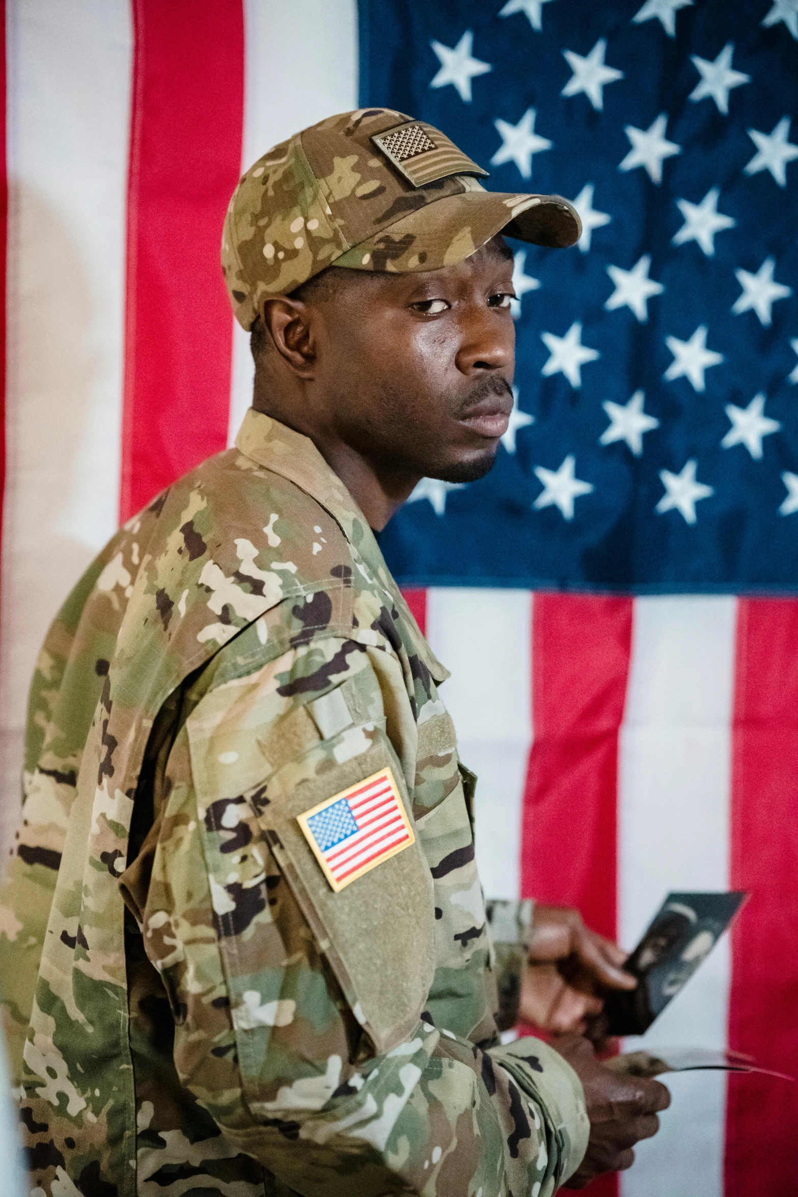 a soldier holding a cell phone in front of an american flag, a portrait, by Alison Geissler, pexels, emmanuel shiru, slide show, looking distracted, full frame image