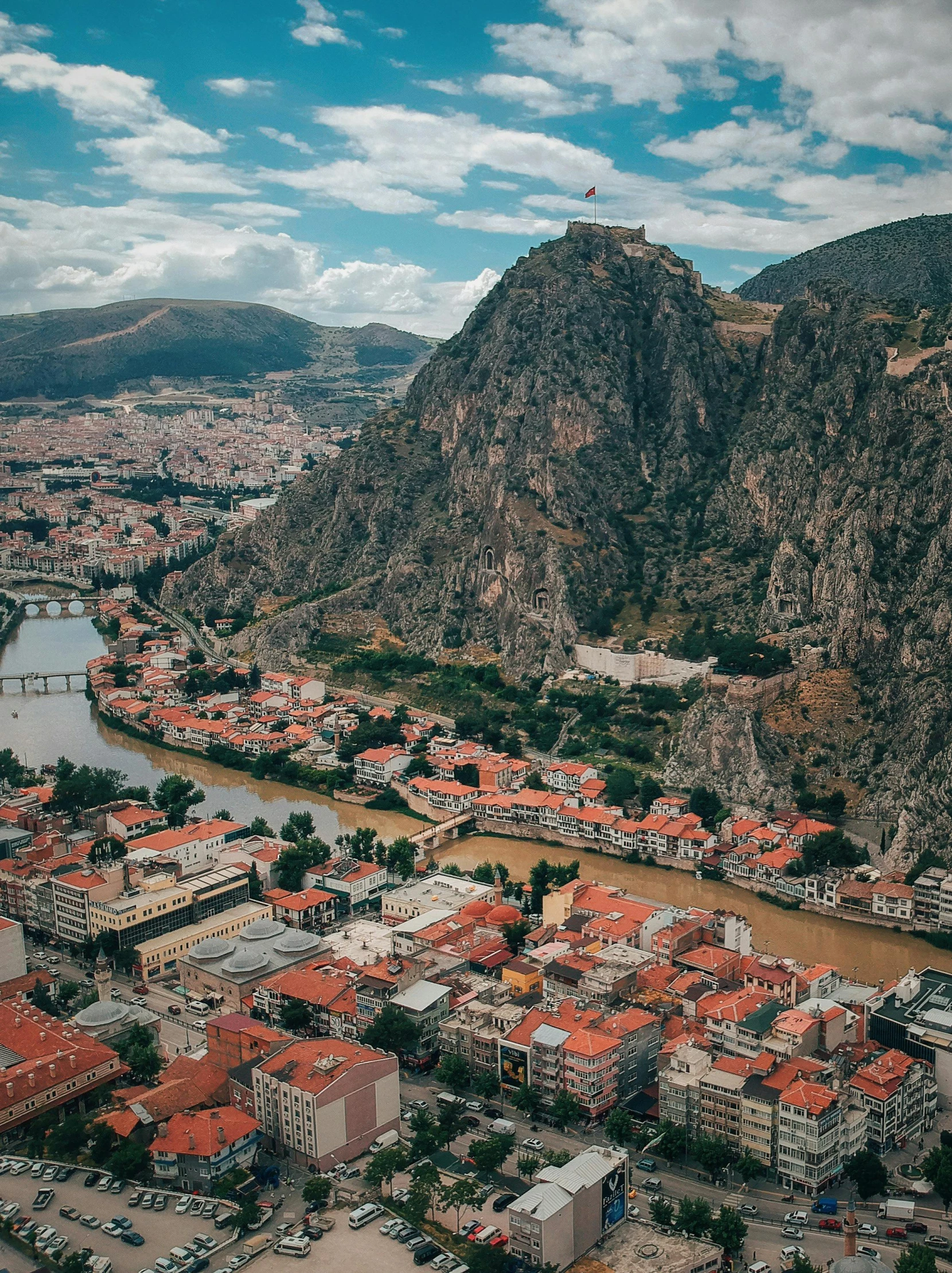 an aerial view of a city with mountains in the background, by Ibrahim Kodra, pexels contest winner, building along a river, color image, square, high quality picture