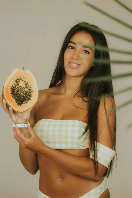 a woman in a bikini holding a slice of papana, by Olivia Peguero, trending on pexels, renaissance, :: madison beer, seeds, skincare, wearing a melon