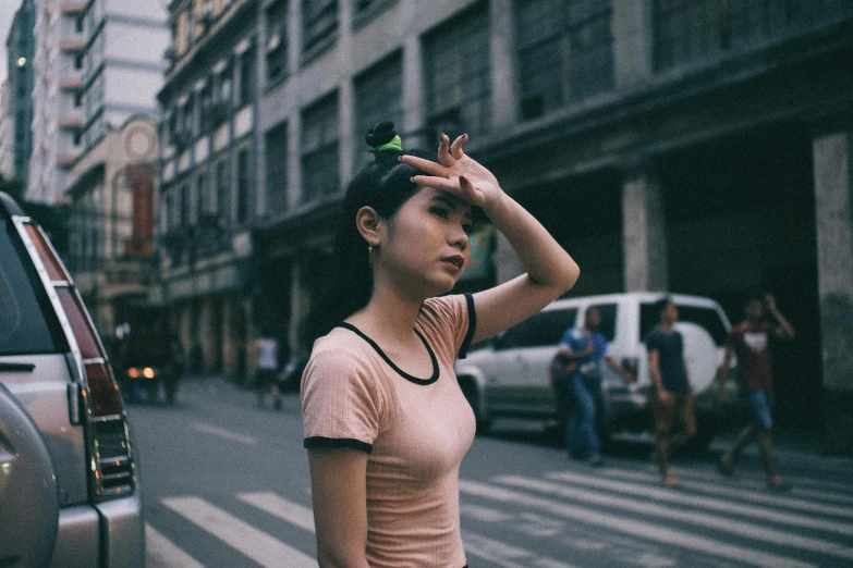 a woman standing on the side of a street, pexels contest winner, realism, asian face, wearing a t-shirt, bare forehead, color film photography