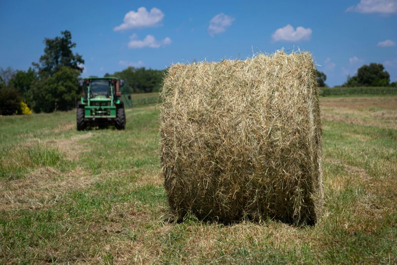 a tractor and a bale of hay in a field, profile image, round-cropped, 1 6 x 1 6, central farm