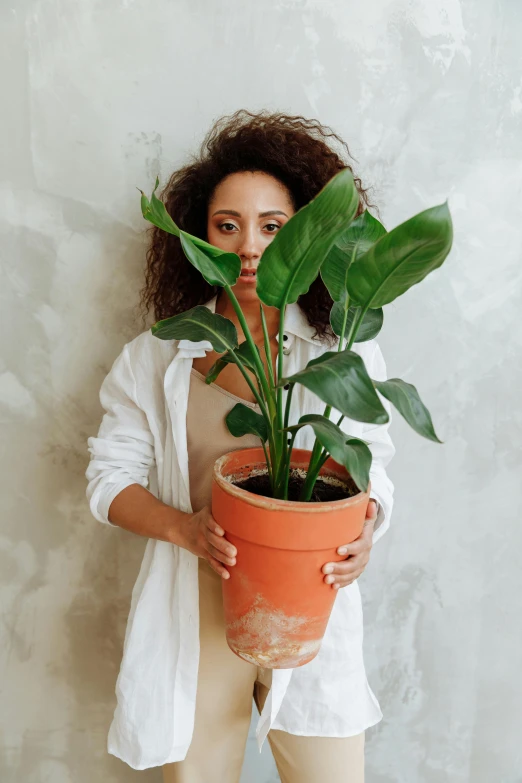 a woman holding a potted plant in front of her face, inspired by Carpoforo Tencalla, pexels contest winner, caramel. rugged, large tall, looking to the right, hispanic