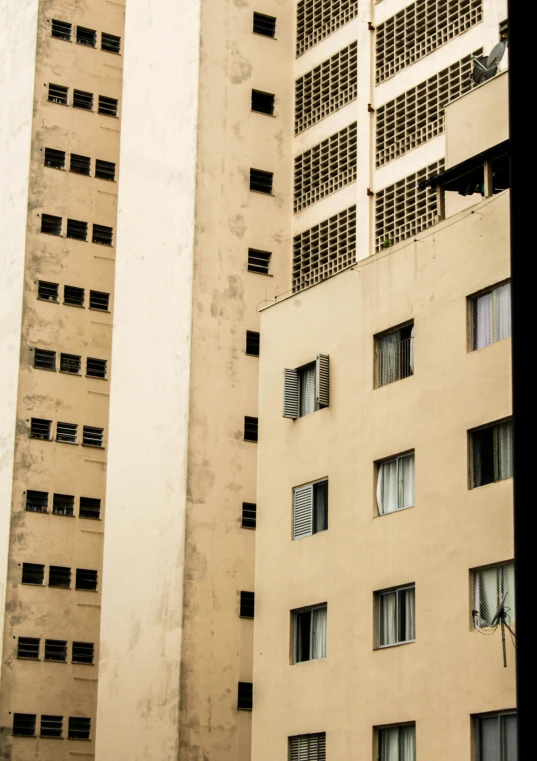 a couple of tall buildings sitting next to each other, inspired by Ricardo Bofill, unsplash, brutalism, streets of salvador, “derelict architecture buildings, sand - colored walls, window ( city )