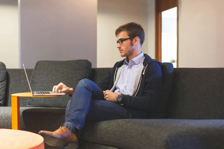 a man sitting on a couch using a laptop, pexels, wearing business casual dress, link from zelda using computer, raphael lecoste, student