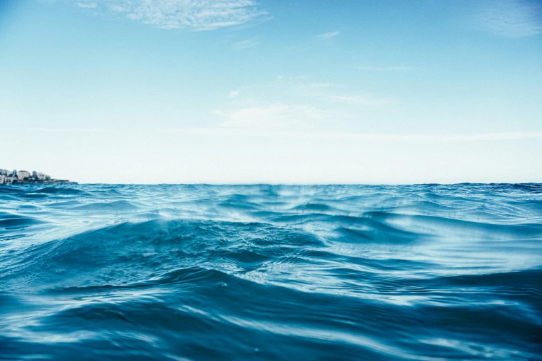 a body of water with a lighthouse in the background, an album cover, by Matthias Stom, unsplash, light blue water, ((waves, water line surface, ultra wide horizon