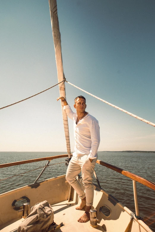 a man standing on the bow of a sailboat, wearing a white button up shirt, doing an elegant pose over you, zac retz, over the horizon