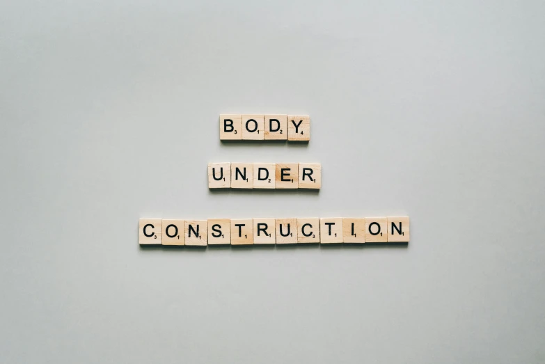 wooden scrabbles spelling body under construction, an album cover, pexels contest winner, constructivism, skincare, gray, {perfect body}, underdimensional