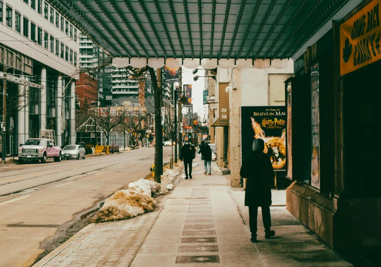 a man walking down a street next to tall buildings, inspired by Vivian Maier, pexels contest winner, toronto city, canopies, people shopping, woman