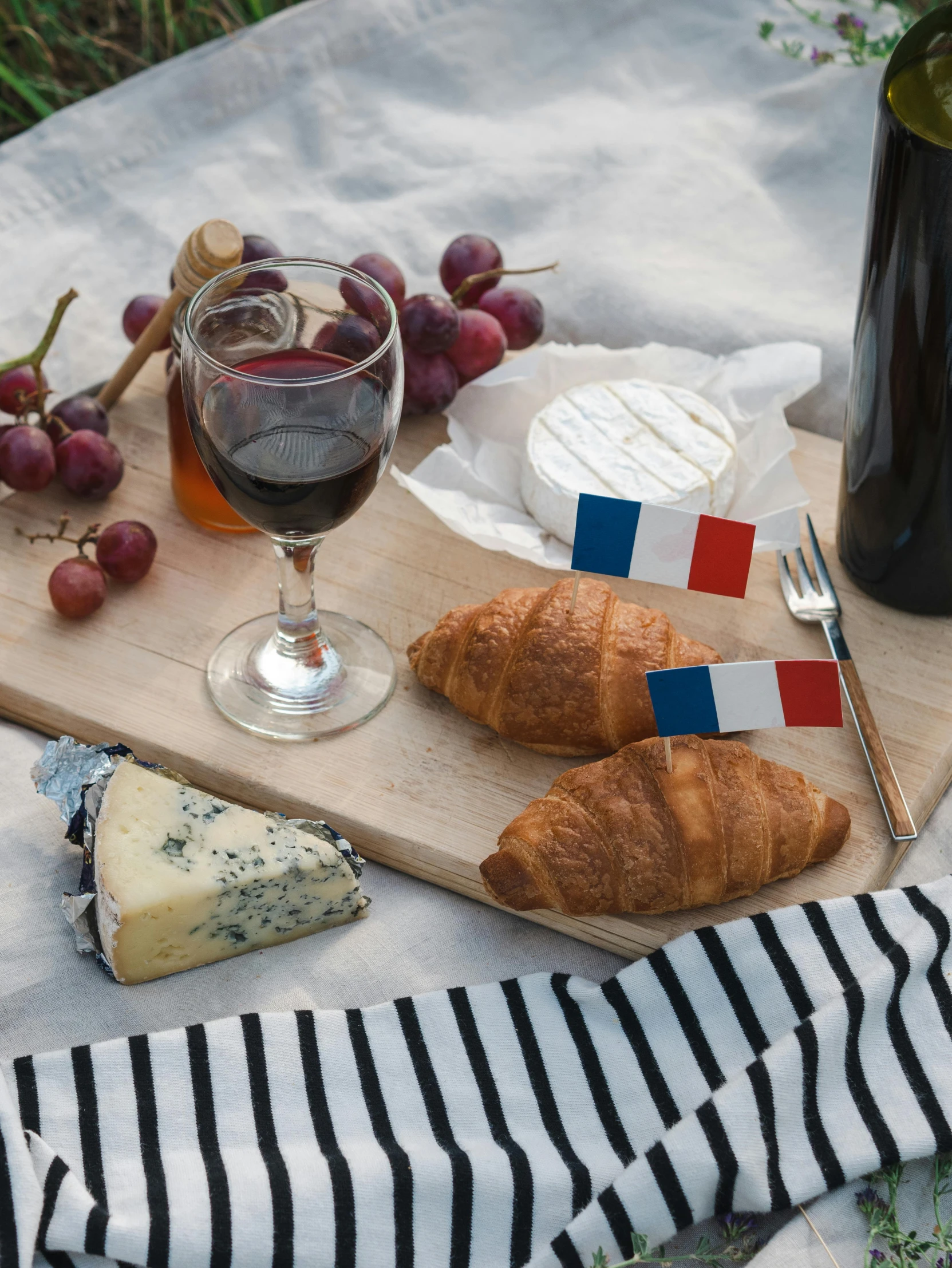 a wooden tray topped with croissants next to a bottle of wine, inspired by Jules Bastien-Lepage, pexels contest winner, figuration libre, french flag, (cheese), neighborhood themed, striped