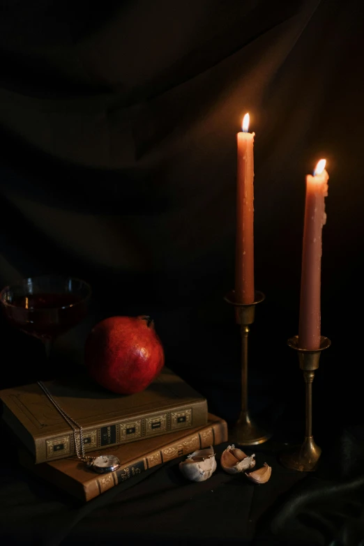 a couple of candles sitting on top of a table, inspired by Joseph Wright of Derby, romanticism, pomegranade, studious chiaroscuro, a wide shot, dark library