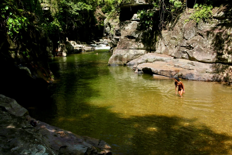 a person standing in a body of water, hurufiyya, tamborine, in between a gorge, tropical pool, fishing