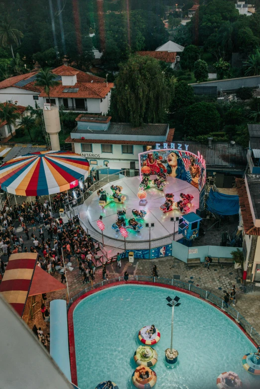 an aerial view of a carnival in a city, fisher price public pool, shot with sony alpha 1 camera, ultrawide angle cinematic view, square