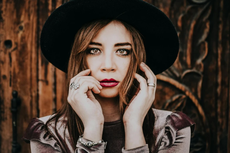 a close up of a person wearing a hat, a portrait, inspired by Elsa Bleda, trending on pexels, antipodeans, attractive brown hair woman, singer songwriter, hands on face, promotional image