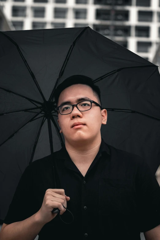 a man in a black shirt holding a black umbrella, inspired by Russell Dongjun Lu, pexels contest winner, discord profile picture, looking serious, non-binary, wearing black glasses