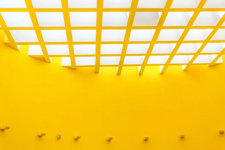 a white toilet sitting in a bathroom next to a yellow wall, inspired by Donald Judd, unsplash contest winner, light and space, sky made of ceiling panels, yellow lanterns, viewed from below, square