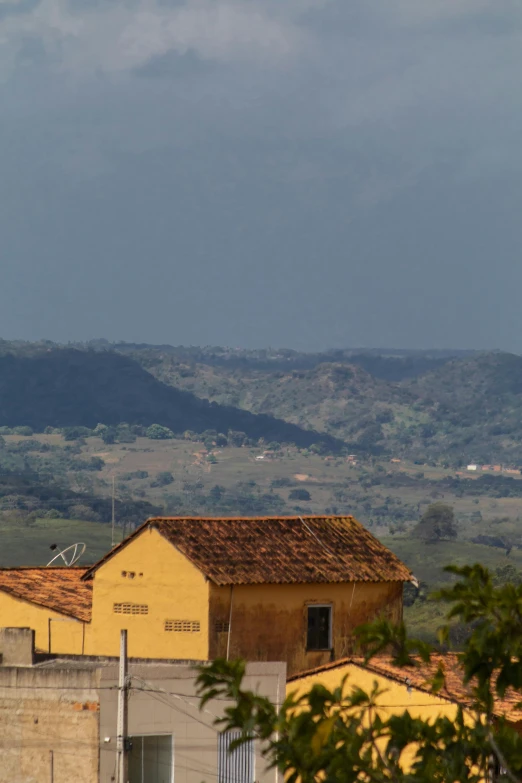 a large jetliner flying over a lush green hillside, by Peter Churcher, flickr, agrigento, next to a farm house and a barn, location ( favela ), distant rainstorm