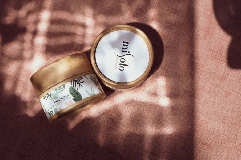 a jar of cream sitting on top of a table, an album cover, unsplash, hurufiyya, relaxed. gold background, miko, photoshoot for skincare brand, in the sun