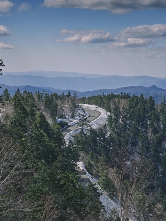 a man riding a snowboard down a snow covered slope, a picture, inspired by LeConte Stewart, unsplash contest winner, renaissance, overlooking a vast serene forest, today\'s featured photograph 4k, early spring, road trip