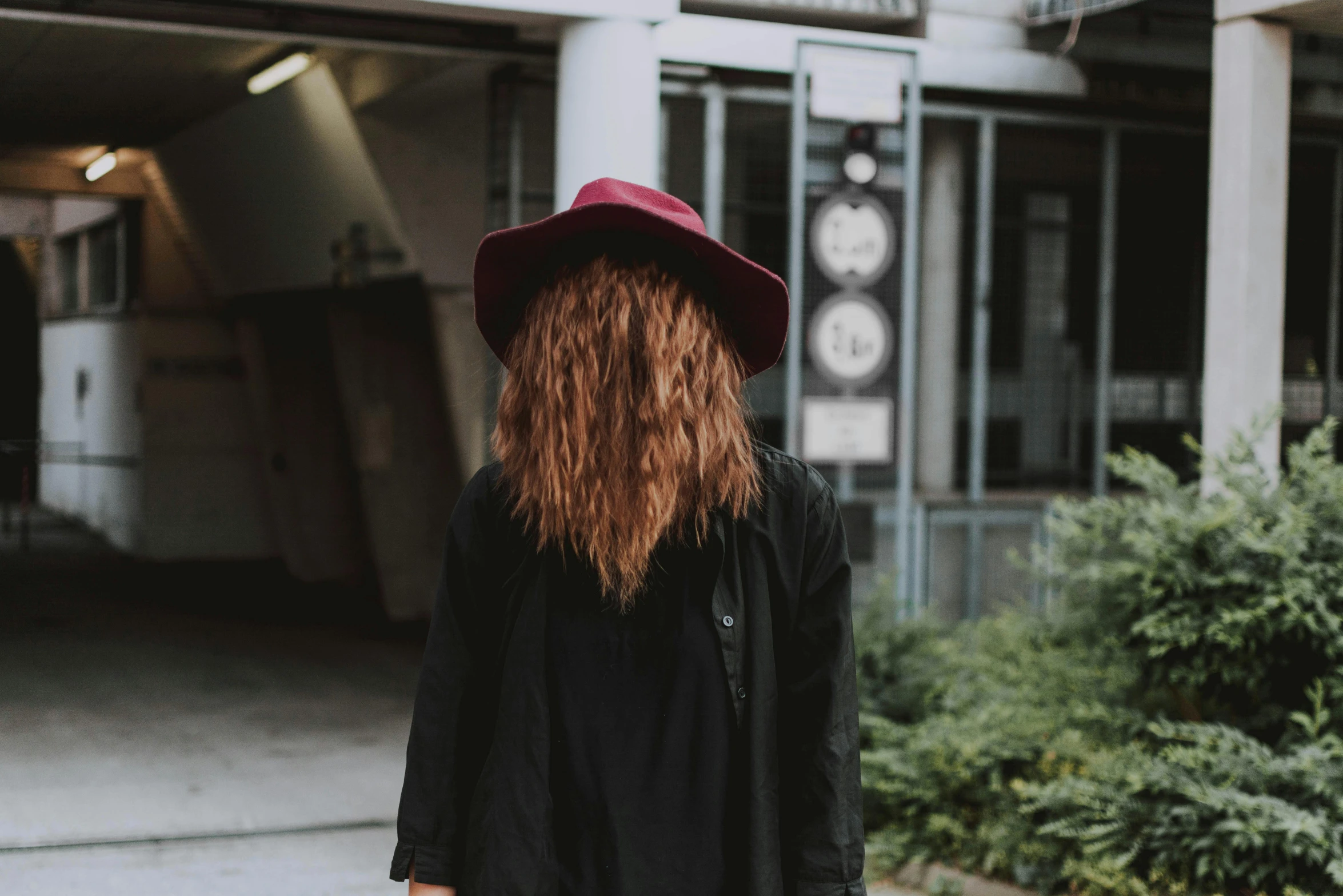 a woman wearing a hat and holding a suitcase, pexels contest winner, antipodeans, long shaggy red hair, back of head, wearing a black jacket, instagram post