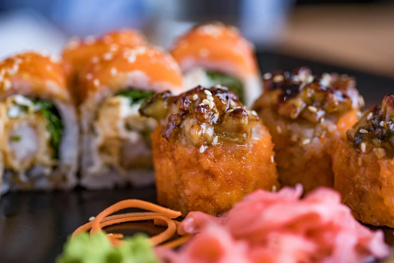 a close up of a plate of sushi, offering a plate of food, caramel, scrolls, square