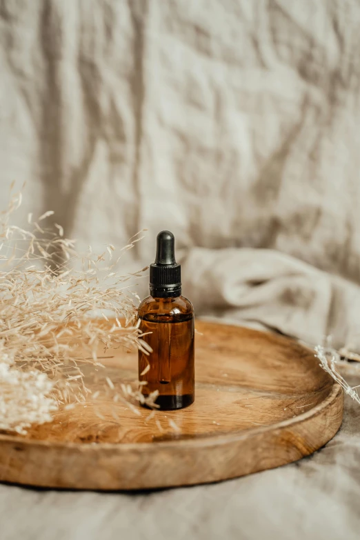 a bottle of essential oil sitting on top of a wooden tray, by Andries Stock, pexels contest winner, photoshoot for skincare brand, thumbnail, linen canvas, handcrafted
