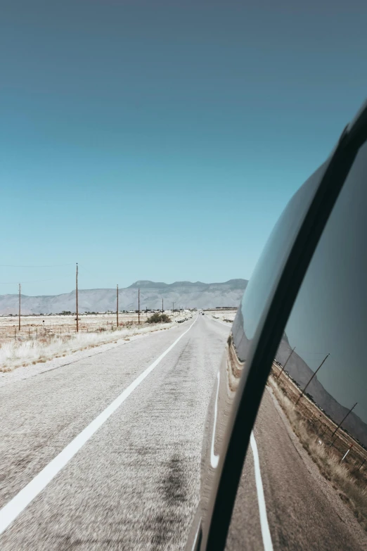 a rear view mirror of a car on the side of the road, trending on unsplash, flat desert, clear blue skies, instagram post, background image