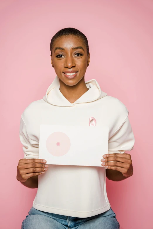 a woman holding a piece of paper with a smiley face drawn on it, an album cover, by Lily Delissa Joseph, pexels contest winner, happening, white and light-pink outfit, ashteroth, olympics, beauty campaign