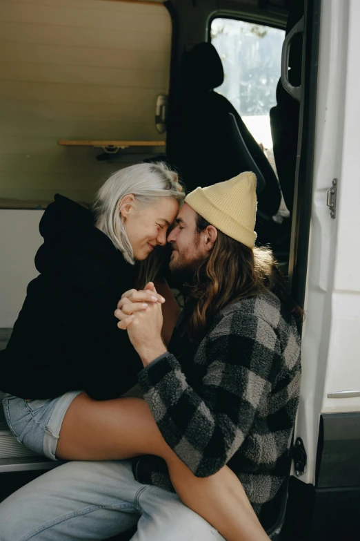 a man and woman sitting in the back of a van, a polaroid photo, by Sara Saftleven, trending on pexels, hugging each other, silver hair and beard, beanie, lachlan bailey