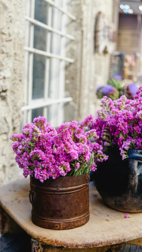 a wooden table topped with vases filled with purple flowers, by Alice Mason, pexels, french village exterior, vibrant pink, cornwall, farming