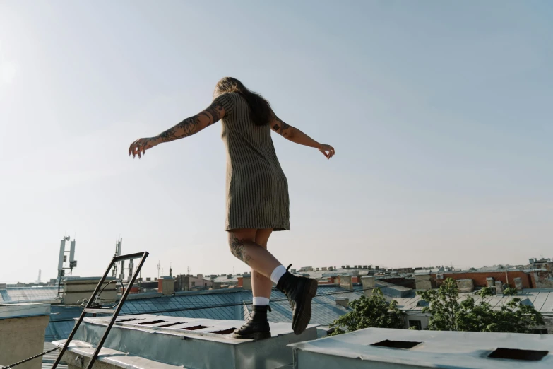 a woman standing on the roof of a building, by Niko Henrichon, pexels contest winner, happening, wearing skirt and high socks, bouncing, wearing a tanktop and skirt, standing on a desk