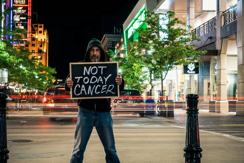 a man holding a sign that says not today cancer, a photo, pexels contest winner, sots art, night-time, thumbnail, greg rutwoski, street pic