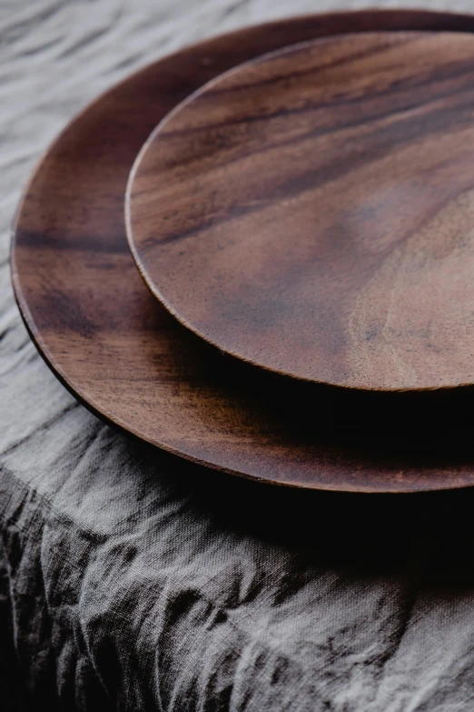 a couple of wooden plates sitting on top of a table, inspired by Jakob Emanuel Handmann, trending on unsplash, dark brown, close up of lain iwakura, “ iron bark, smooth matte