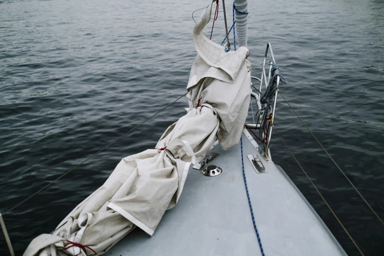 a sail boat sitting on top of a body of water, drenched clothing, grey rubber undersuit, ignant, thumbnail