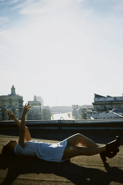 a man riding a skateboard down the side of a road, an album cover, inspired by Ruth Orkin, happening, girl sitting on a rooftop, laying on beach, seville, sunny sky