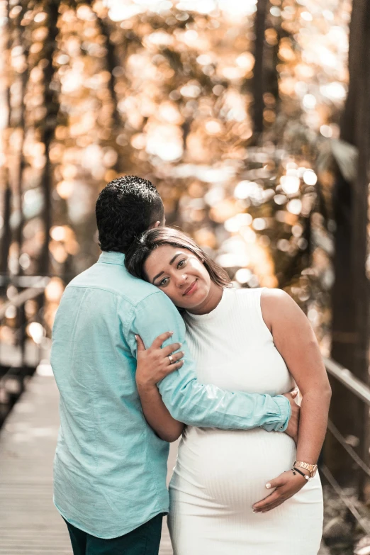 a pregnant woman standing next to a man on a bridge, a picture, pexels contest winner, happening, hugging each other, hispanic, in a jungle environment, backlighted