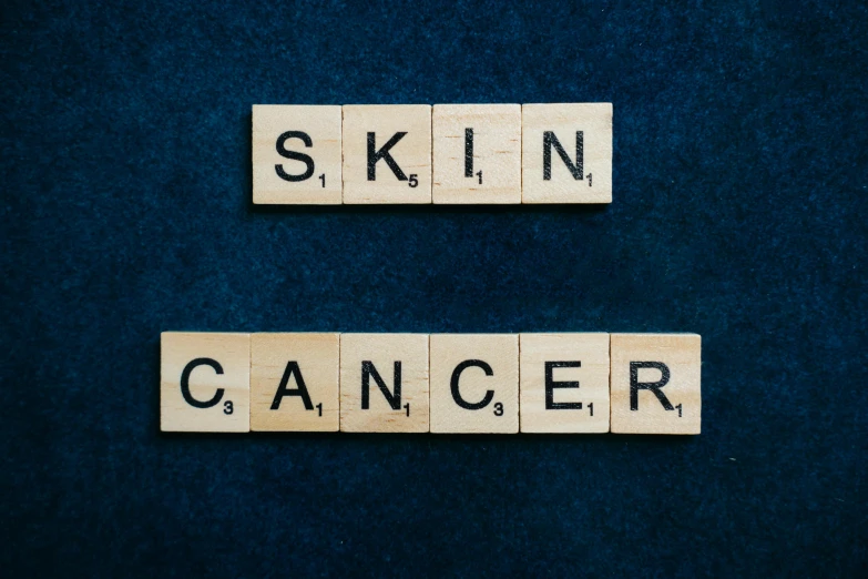 wooden scrabbles spelling skin cancer on a blue background, an album cover, shutterstock, dark grey skin, photoshoot for skincare brand, 2070, skins