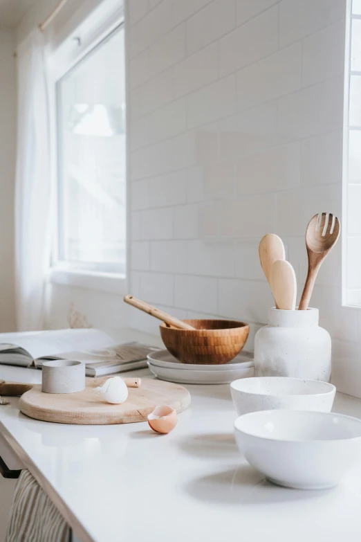 a kitchen counter topped with bowls and wooden utensils, trending on unsplash, clean white background, dwell, set photo