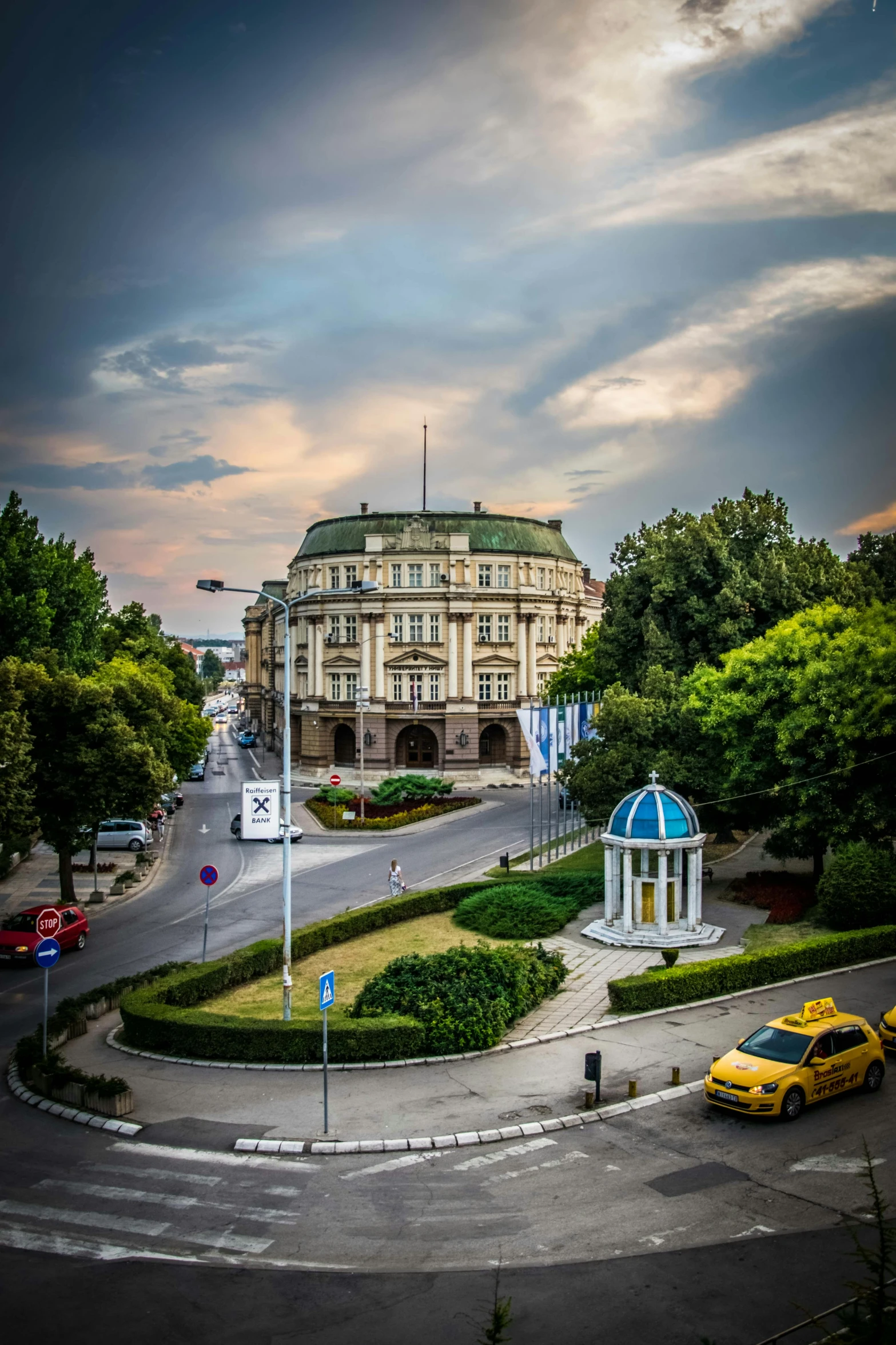 a large building sitting on the side of a road, by Adam Szentpétery, palace on top of the hill, high view, rotunda, downtown